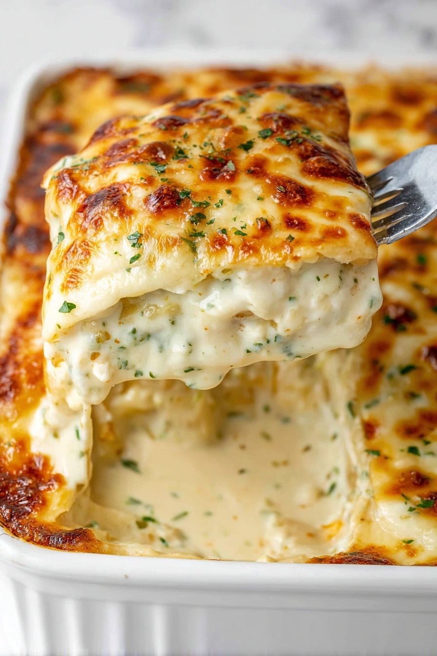 The image shows a close-up of a creamy baked dish being lifted from a white ceramic baking dish with a fork. The dish has three main layers: a browned, bubbly, golden cheese crust on top with small green herb flecks, a thick, creamy, off-white sauce layer with visible bits of herbs and spices in the middle, and a soft, melted layer of white cheese underneath. The baking dish has elegant, curved handles and sits on a white marbled surface. Photo taken with an iphone --ar 2:3 --v 7