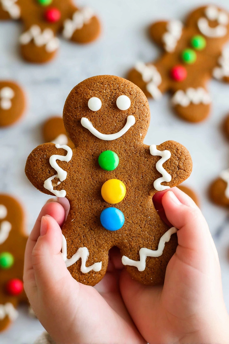 A brown gingerbread cookie shaped like a person is being held by two small hands, with one hand on each side. The cookie has three colorful round candies in blue, red, and yellow placed vertically in the center. White icing forms two eyes and a smiling mouth at the top, wavy lines on both arms near the shoulders, and zigzag patterns on the bottom of the legs. Other similar gingerbread cookies are blurred out in the background, and everything is set on a white marbled surface. photo taken with an iphone --ar 2:3 --v 7