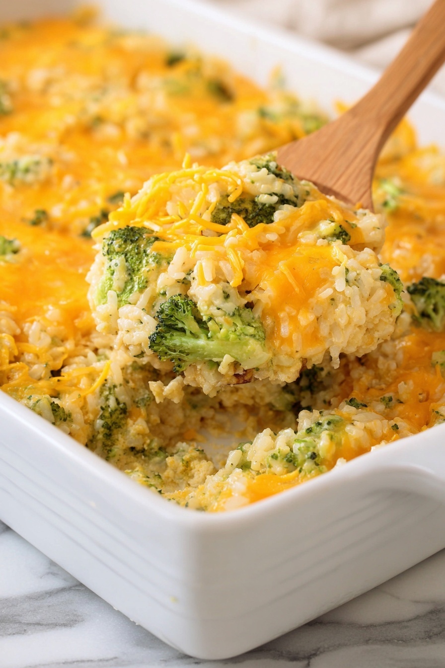 The image shows a white rectangular baking dish filled with a casserole that has two visible layers. The bottom layer consists of a creamy mixture with green broccoli pieces mixed throughout, giving it a chunky texture. The top layer is a generous amount of melted cheddar cheese, bright orange in color, spread evenly over the broccoli base. A wooden spoon is lifting a portion of the casserole, showing the thick, mixed texture of the broccoli and cheese. The dish is placed on a white marbled surface. Photo taken with an iphone --ar 2:3 --v 7