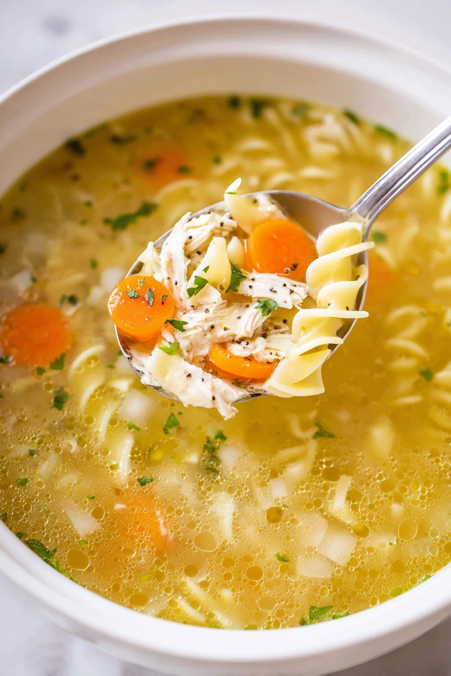 This image shows a white bowl filled with clear chicken noodle soup, with a spoon lifting some of the ingredients. The soup has a golden broth base, with layers of chopped orange carrots and small pieces of pale green celery scattered throughout. There are soft, curly egg noodles in light yellow twisted shapes, mixed with shredded white chicken pieces. Small green specks of parsley or herbs float on the surface and inside the broth. The white marbled texture can be seen around the bowl. photo taken with an iphone --ar 2:3 --v 7