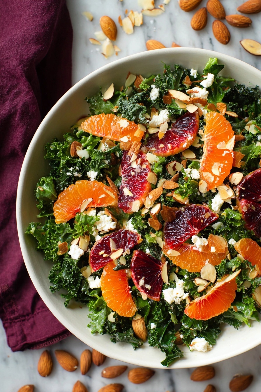 A white bowl filled with a layered salad starting at the bottom with dark green kale leaves, chopped finely. On top are bright orange tangerine segments and deep red blood orange slices evenly spread around. Scattered on the salad are light beige sliced almonds and small white crumbles of cheese, adding texture and contrast. The colors pop against the white bowl, with a white marbled surface and a dark red cloth partly visible underneath. Some almond slices and kale pieces are also on the surface around the bowl photo taken with an iphone --ar 2:3 --v 7