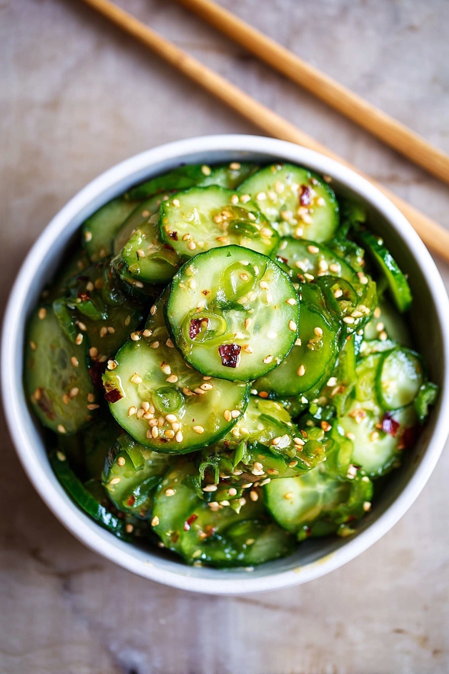 A white bowl filled with a fresh cucumber salad sits on a white marbled surface. The salad has many round cucumber slices, bright green with their skin on, layered thickly inside the bowl. Sprinkle of light brown sesame seeds covers the cucumber slices evenly, adding texture. Small pieces of chopped green onions are mixed throughout, giving extra green color and a bit of rough texture. The bowl is simple and smooth, contrasting with the detailed cucumber salad inside. A pair of light brown chopsticks rests in the background on the white marbled surface. photo taken with an iphone --ar 2:3 --v 7