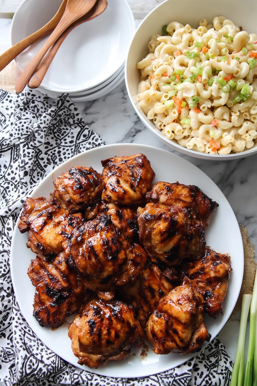 On a white plate, there is a stack of nine grilled chicken thighs with a shiny, dark brown glaze and visible grill marks on each piece; the chicken pieces have a slightly charred texture at the edges, showing a rich, caramelized color. Next to this plate is a white bowl filled with creamy macaroni salad that has small chunks of light pink pieces mixed in, topped with finely chopped light green onions for color. The setting includes a wooden spoon above the plates, part of a white marbled surface beneath, and a patterned cloth under the chicken plate. Photo taken with an iphone --ar 2:3 --v 7